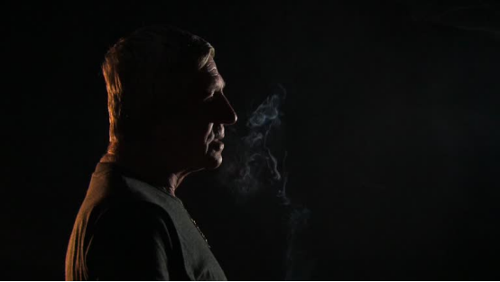 Person uses rolling paper to prepare a pre-roll in low light, mastering effortless rolling skills