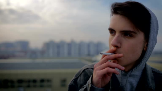 Person uses rolling paper to roll a cigarette, finding calm through the meditative art of rolling