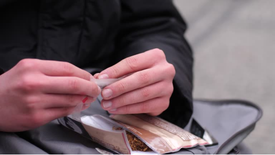 Person carefully rolls rolling paper, highlighting how the ritual of preparation matters as much as the final result in the psychology of rolling paper