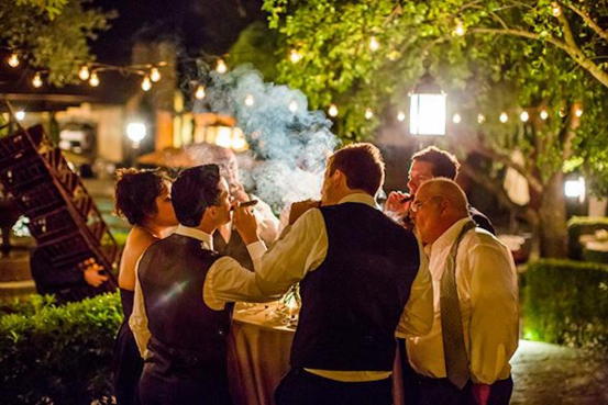 Guests Enjoying Cigarettes at Elegant Nighttime Dinner Party, Highlighting Premium Rolling Papers like HONEYPUFF, HORNET, and Gorilla to Elevate Hosting
